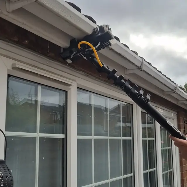Water-fed brush cleaning a white gutter